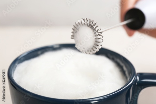 Using milk frother device in cup, closeup