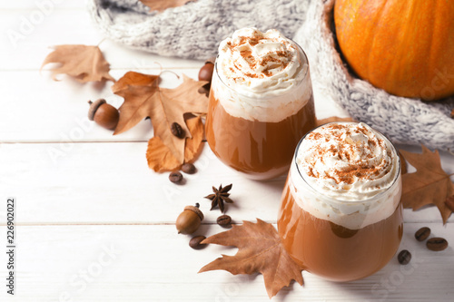 Glasses with tasty pumpkin spice latte and space for text on wooden table