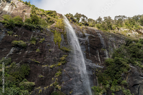Waterfall flowing over a cliff in Milford Sound, New Zealand