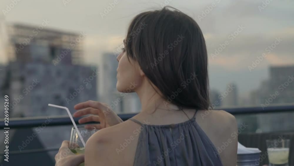 Young woman drinking cocktail sitting in skybar
Young woman drinking cocktail sitting in skybar