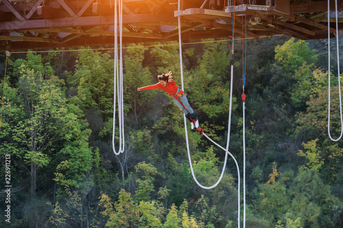 women jumping down bungee jump sport in sunset and light flare