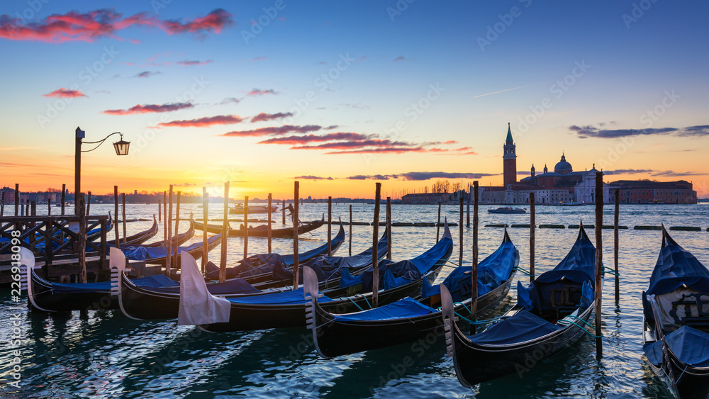 Venice with famous gondolas at sunrise, Italy. Gondolas in lagoon of Venice on sunrise, Italy. Venice with gondolas on Grand Canal against San Giorgio Maggiore church.