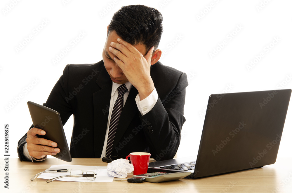 Asian business man using tablet device and having headache on white backgrounds Asian business man using tablet device and having headache on white backgrounds