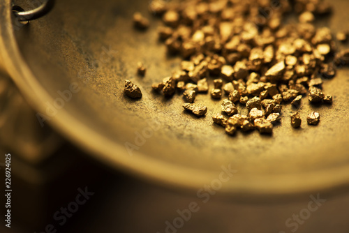 Trade and exchange. Weighing a gold nugget on a old brass scale dish.for trading. Shallow depth of field. photo