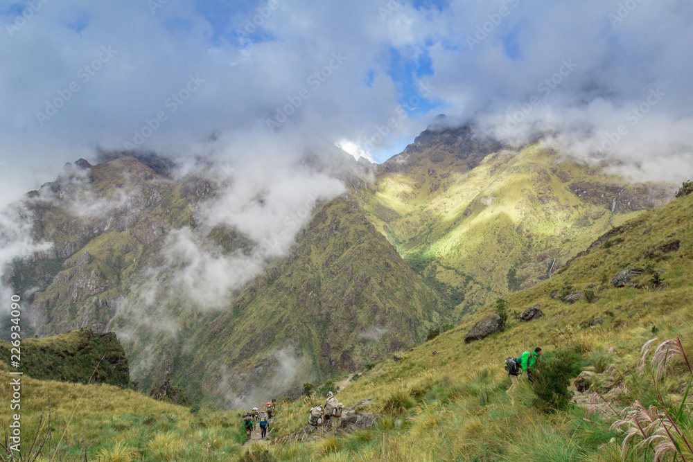 Blue cloudy sky above verdant green mountains and hikers on the Inca Trail in Peru