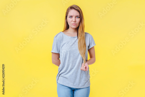 Foto Girl on a yellow background is puzzled and looks with a passively aggressive look