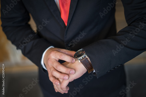 The groom wears and adjust a wristwatch. The groom looks at his watch. Wedding detail preparation.