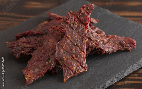 Photography Pile of Black Pepper Beef Jerky on a Rustic Wooden Table