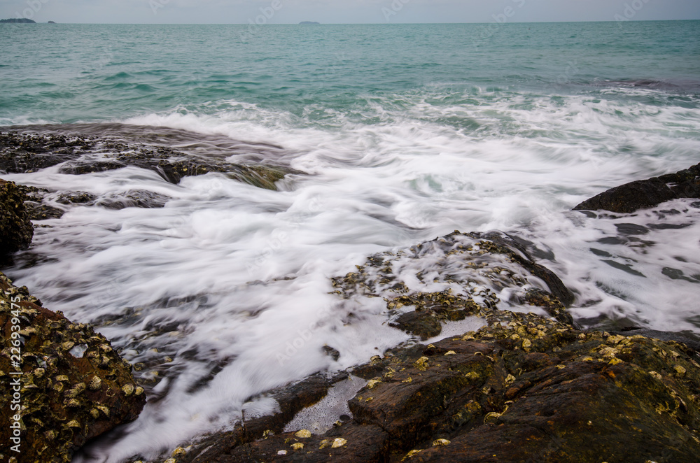 Sea waves crashing to rocks creating foam.