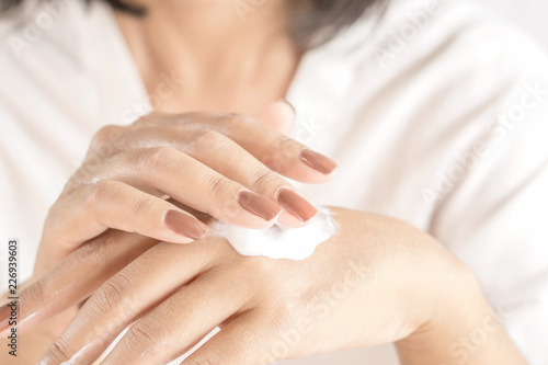 beautiful woman hand with nail polish applying hand cream 