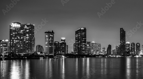 Cityscape of modern building near the river in the evening. Modern architecture office building. Skyscraper with evening sky. Black and white tone picture. Night photography of riverfront building.