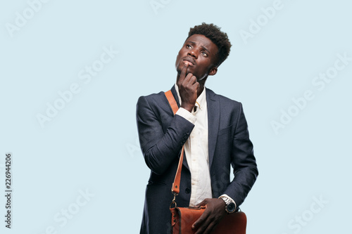 young black businessman With a confused and thoughtful look, looking sideways, thinking and wondering between different options. photo