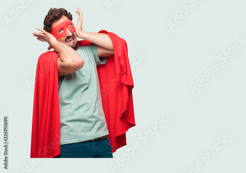 crazy man as a super hero with both hands covering ears to protect them from an uncomfortable, loud, annoying noise. Lateral or side view. photo