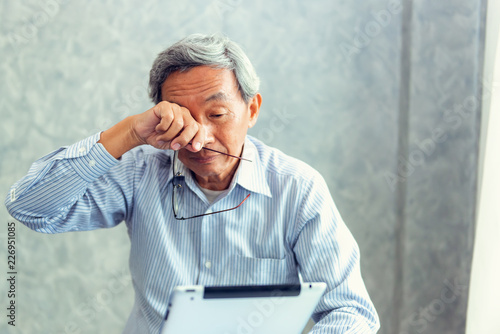 Senior Asian Man Has Eyes Problems With His Vision While Trying to Read Message in Tablet. Close-Up of Elderly Old Male Having Long/Far Sighted and Eye Fatigue When He Looking Screen Tablet Long Time photo