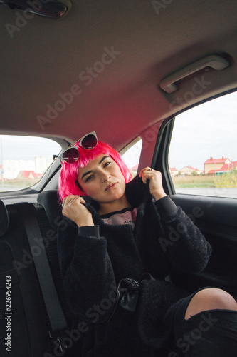 woman in a pink wig in a car