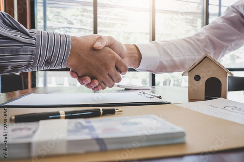 Real estate broker agent and customer shaking hands after signing contract documents for realty purchase, Bank employees congratulate, Concept mortgage loan approval