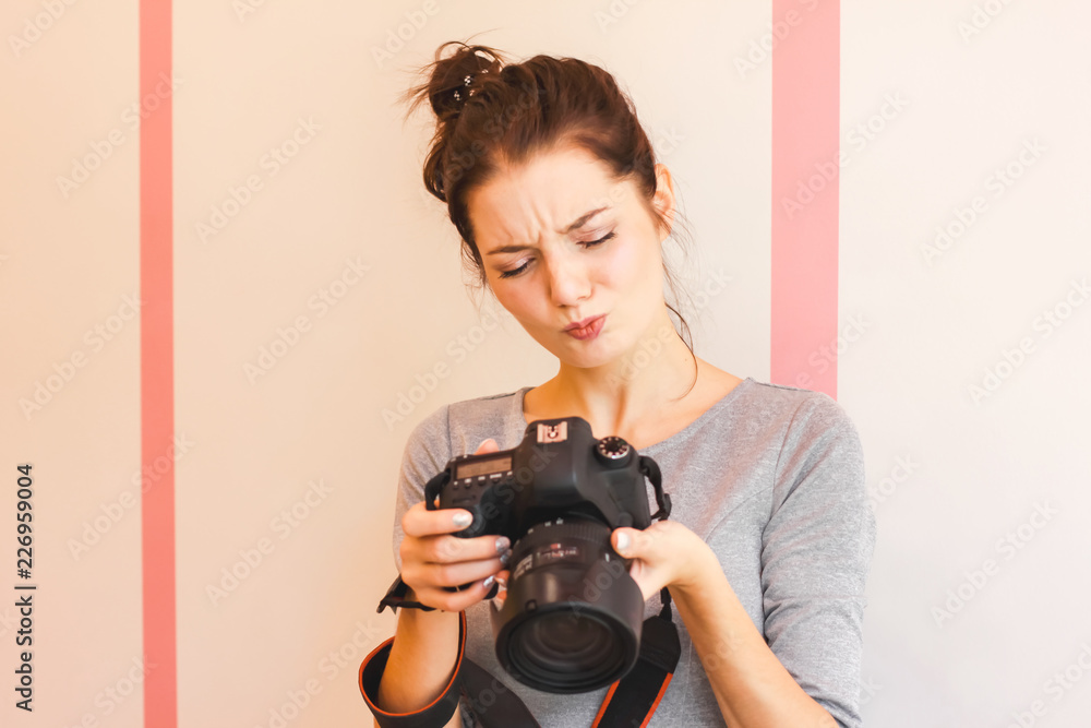Pretty girl photographer looks into her camera and makes funny face Pretty girl photographer looks into her camera and makes funny face