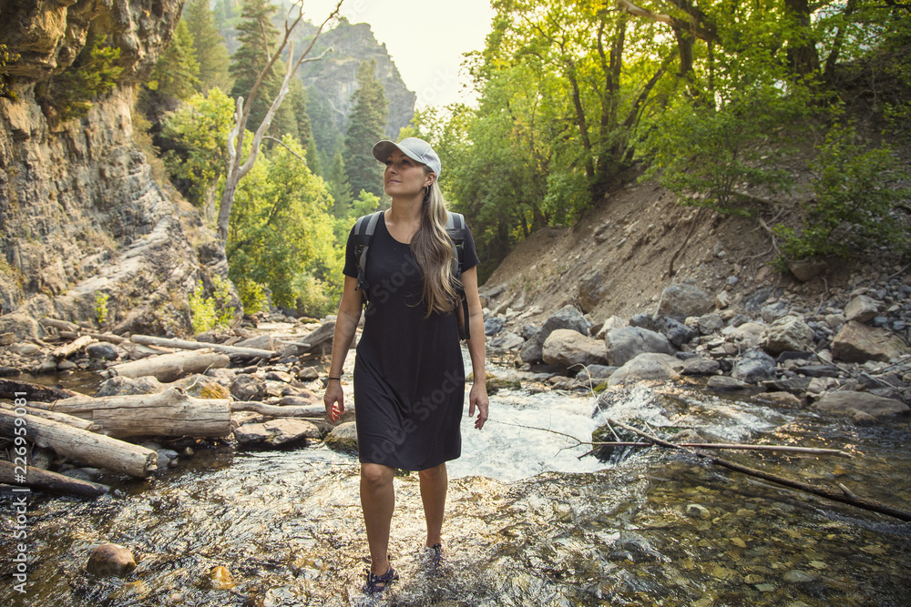 Attractive Woman hiking across a shallow mountain stream while on vacation in the Western United States. Candid photo of an active female enjoying the outdoors