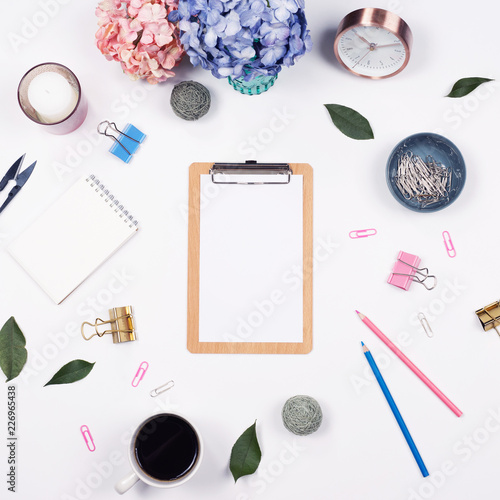 Feminine desk workspace frame mockup with beauty arrangement of bouquet hydrangeas, clipboard, notebook, pencil and candle on white background with copy space. Flat lay, Top view.