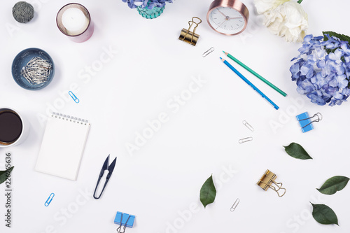 Feminine desk workspace frame with beauty arrangement of bouquet hydrangeas, laptop, clipboard, notebook, pencil and candle on white background. Flat lay, Top view office table desk with copy space. 