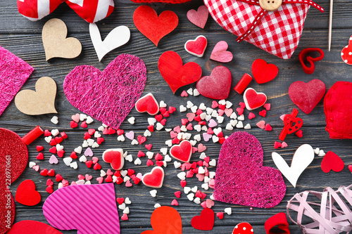 Different color hearts with candies on wooden background