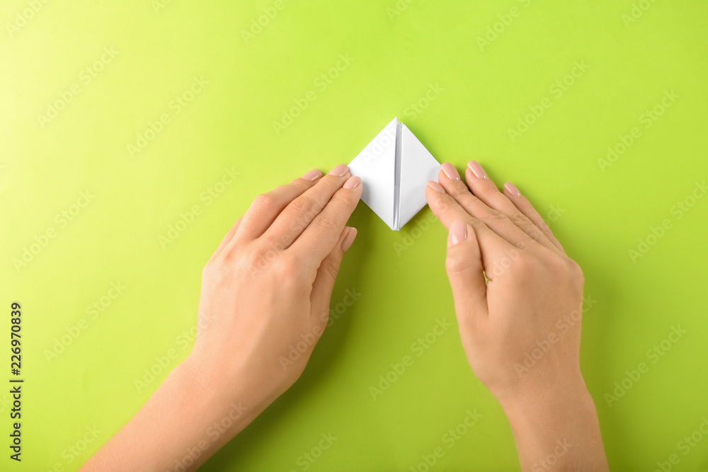 Woman making origami boat on color background - obrazy, fototapety, plakaty 