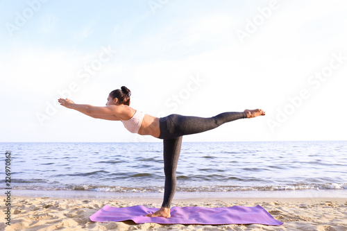 Woman practicing yoga on se...