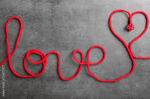 Word LOVE made of red thread on grey background