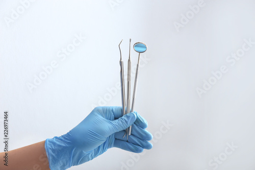 Dentist holding stainless instruments on light background