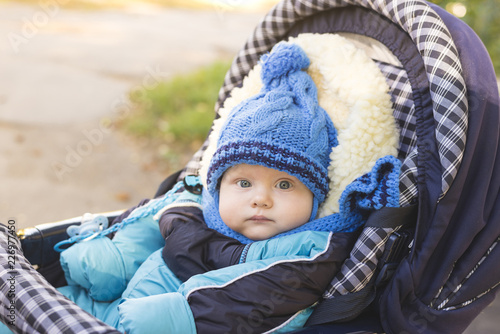 A small child in a hat and scarf sitting in a stroller