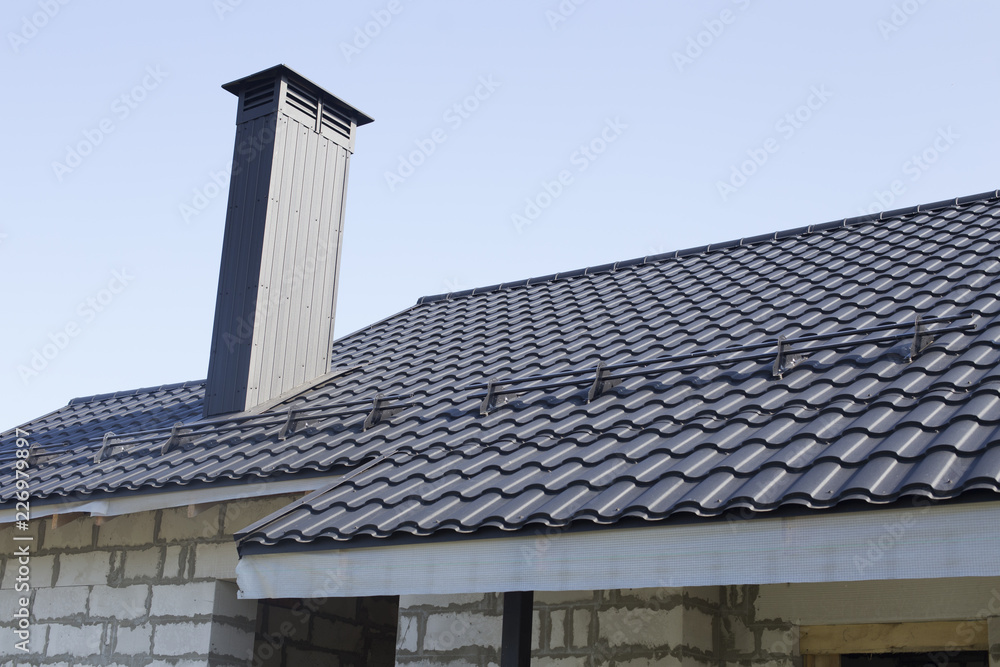 The roof is made of black metal with a chimney. The concept of construction.
