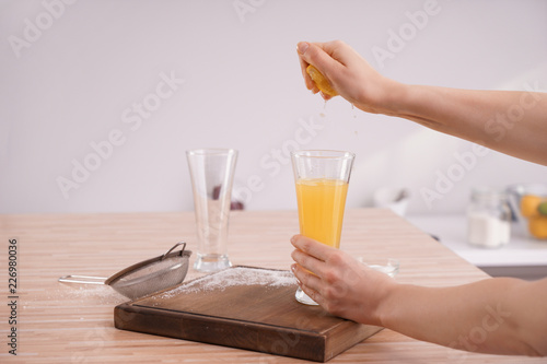 Woman squeezing fresh lemon juice in kitchen
