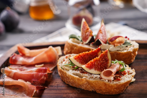 Tasty sandwiches with ripe fig and prosciutto on wooden board