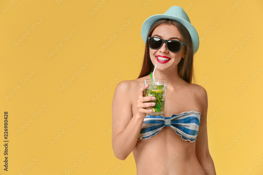 Beautiful woman in swimming suit and with tasty summer cocktail on color background Beautiful woman in swimming suit and with tasty summer cocktail on color background