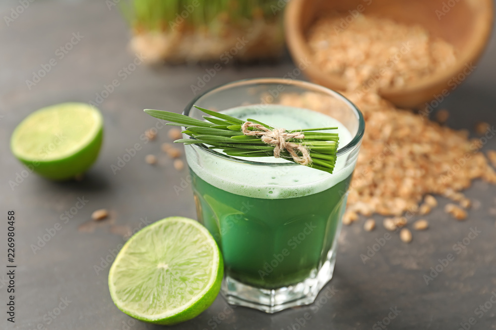 Fototapeta premium Glass of wheat grass juice on grey table