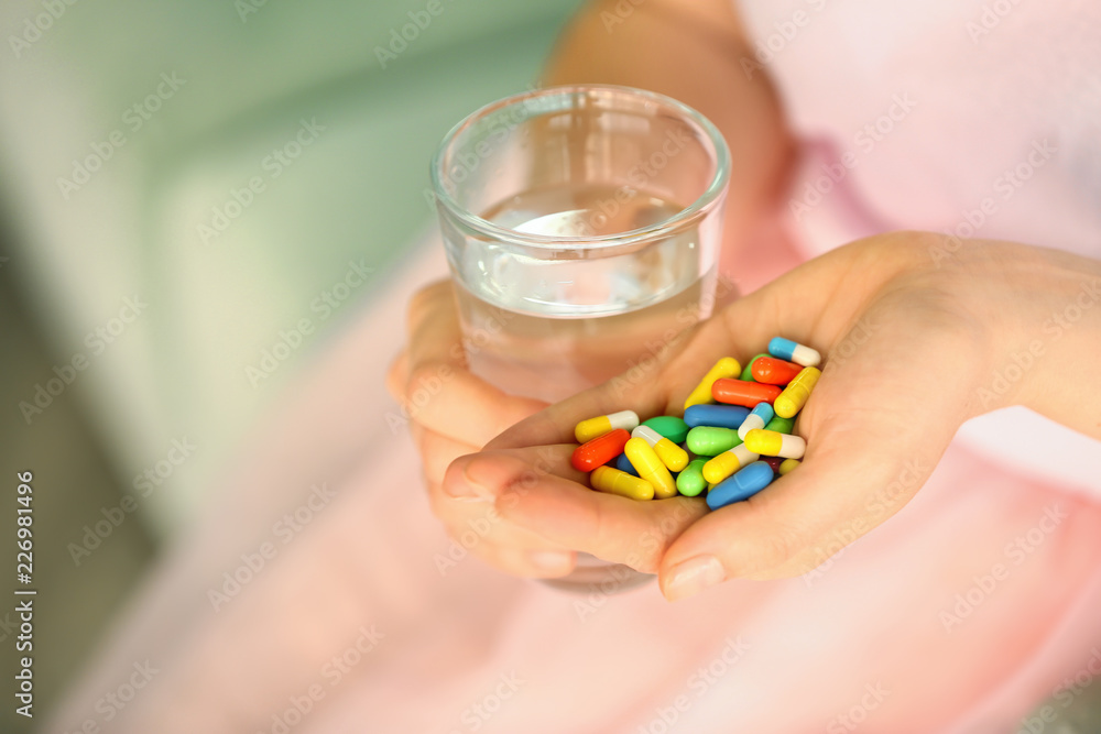 Woman with pills and glass of water, closeup Woman with pills and glass of water, closeup