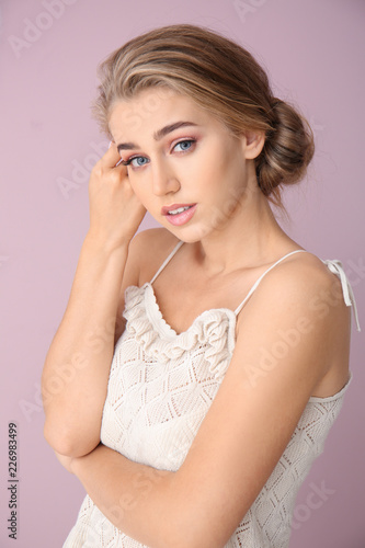 Beautiful young woman with nude makeup on color background