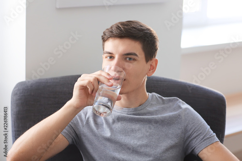 Young man drinking water at...