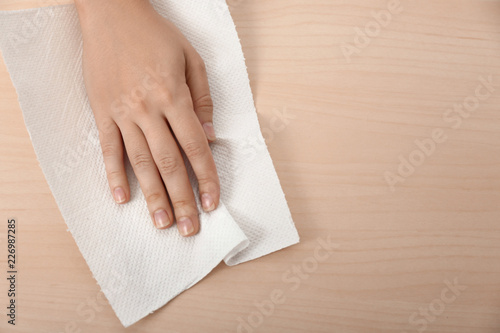 Woman wiping wooden table with paper towel