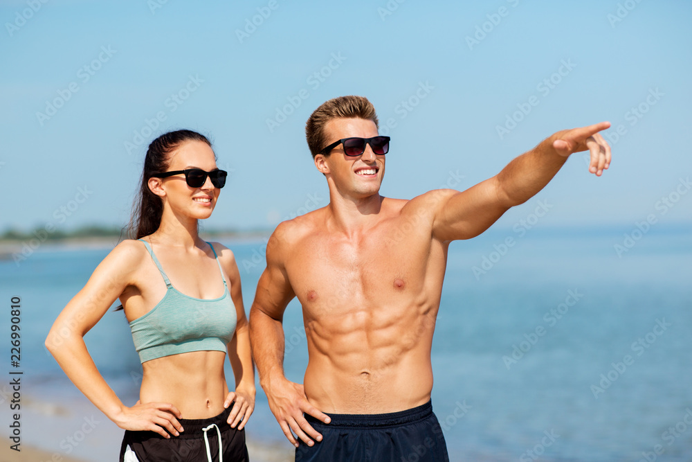 fitness, sport and lifestyle concept - happy couple in sports clothes and sunglasses on beach fitness, sport and lifestyle concept - happy couple in sports clothes and sunglasses on beach