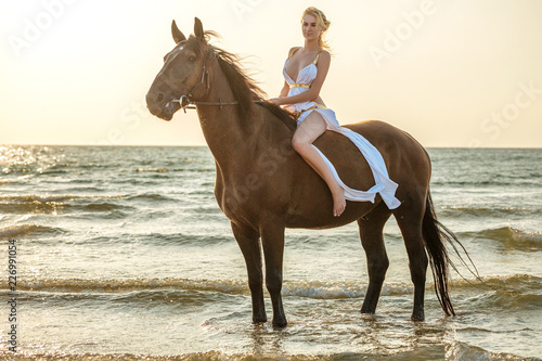 beautiful young woman in white dress by the sea with horse