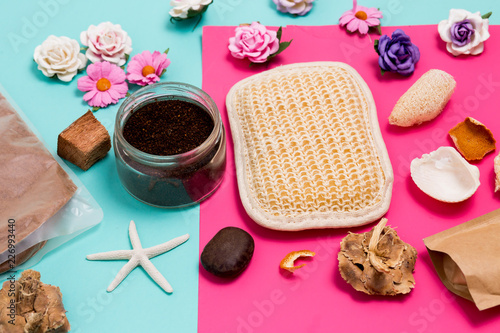 Close-up of colorful Spa and care facilities, small flowers, scrub, washcloth and seashells on pink and blue background