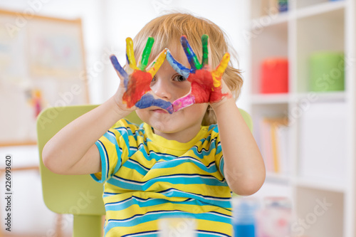 Fotografie cute cheerful kid with hands painted in bright colors