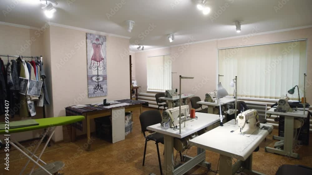 Empty designer atelier interior with tables and sewing machines. Equipped fashion tailoring studio indoors with clothes and reels of threads, no people. Empty designer atelier interior with tables and sewing machines. Equipped fashion tailoring studio indoors with clothes and reels of threads, no people.