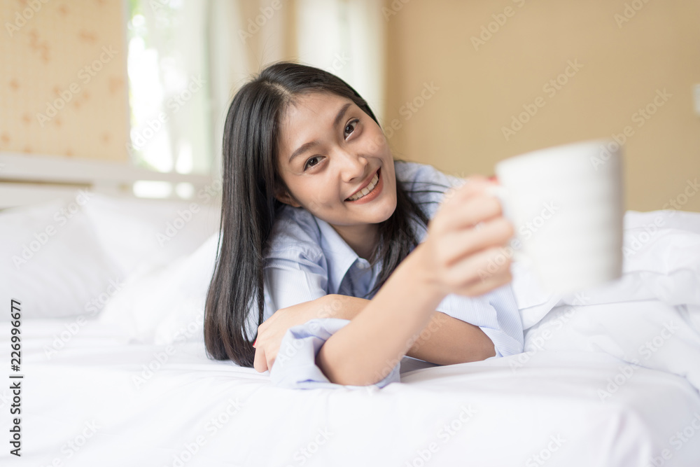 Happy Woman laying and have a breakfast coffee on bed after wake up Happy Woman laying and have a breakfast coffee on bed after wake up