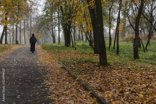 Autumn morning in the park and leaving woman in black.