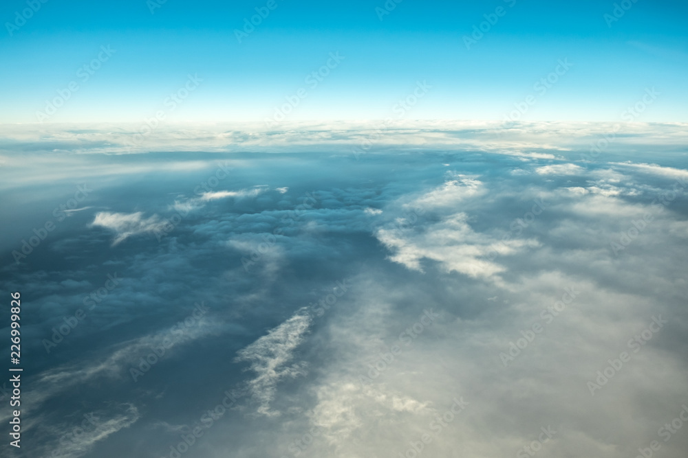 Clouds in blue sky, aerial view from airplane window. Cloudscape natural background.