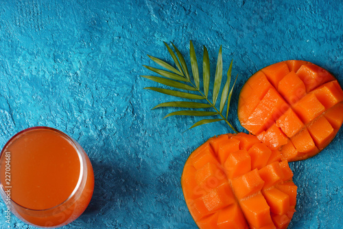 The layout on a bright blue background. Mango, a glass of juice and a palm leaf.