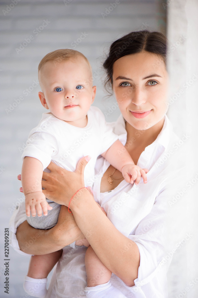Mother and child in a white room. Mom and baby boy in diaper pla Mother and child in a white room. Mom and baby boy in diaper pla