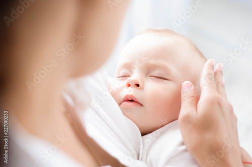 Baby sleeping on the mother's chest. Young mother cuddling baby photo